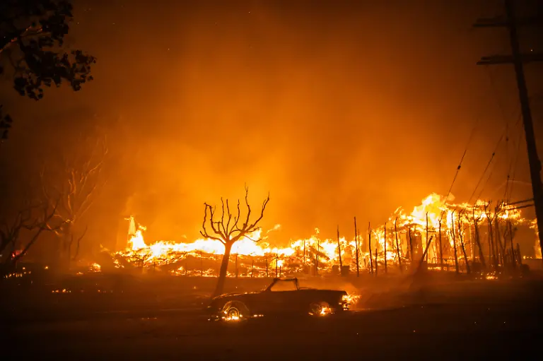 LOS-ANGELES-CALIFORNIA-JANUARY-8-Flames-from-the-Palisades-Fire-burns-a-car-and-homes-during-a-powerful-windstorm-on-January-8-2025-in-the-Pacific-Palisades-neighborhood-of-Los-Angeles-California-The-fast-moving-wildfire-is-threatening-homes-in-the-coastal-neighborhood-amid-intense-Santa-Ana-Winds-and-dry-conditions-in-Southern-California