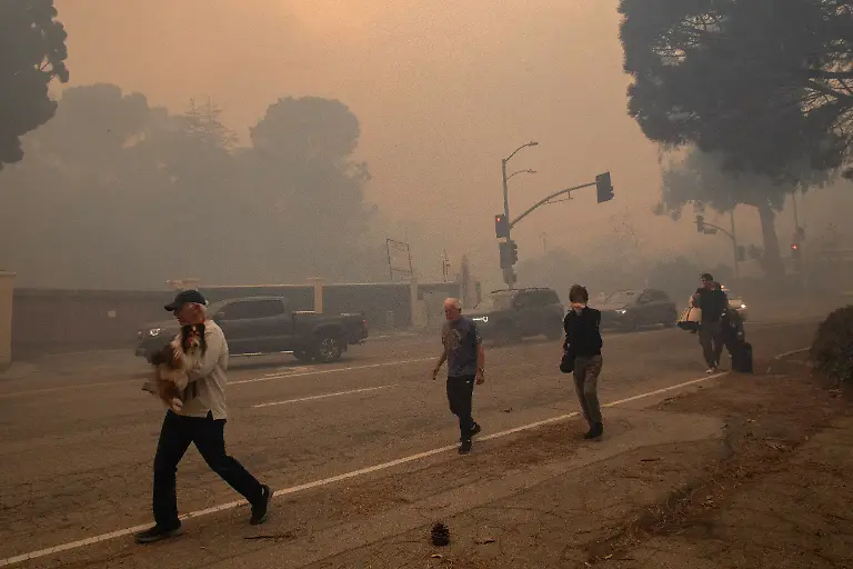 LOS-ANGELES-CALIFORNIA-JANUARY-7-People-evacuate-along-Sunset-Boulevard-as-the-Palisades-Fire-burns-amid-a-powerful-windstorm-on-January-7-2025-in-the-Pacific-Palisades-neighborhood-of-Los-Angeles-California-The-fast-moving-wildfire-is-threatening-homes-in-the-coastal-neighborhood-amid-intense-Santa-Ana-Winds-and-dry-conditions-in-Southern-California