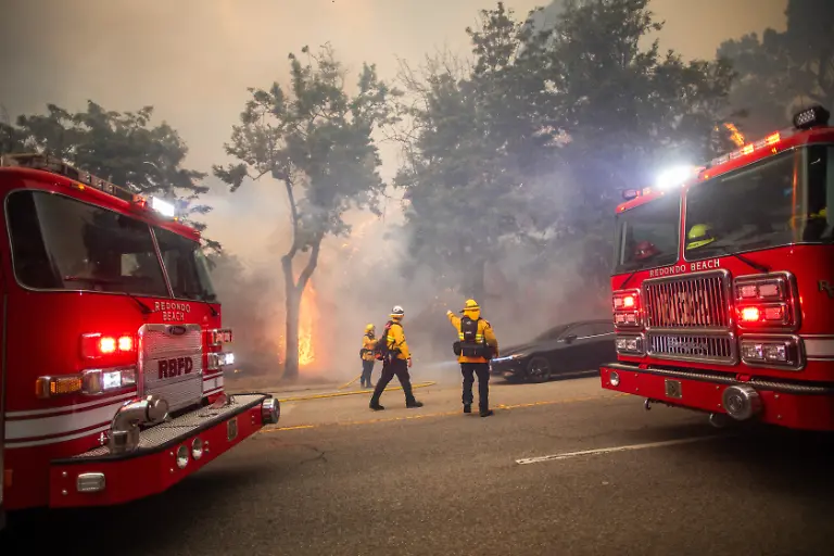 LOS-ANGELES-CALIFORNIA-JANUARY-7-Firefighters-watch-flames-from-the-Palisades-Fire-on-Sunset-Boulevard-amid-a-powerful-windstorm-on-January-7-2025-in-the-Pacific-Palisades-neighborhood-of-Los-Angeles-California-The-fast-moving-wildfire-is-threatening-homes-in-the-coastal-neighborhood-amid-intense-Santa-Ana-Winds-and-dry-conditions-in-Southern-California