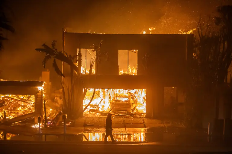 LOS-ANGELES-CALIFORNIA-JANUARY-8-A-firefighter-watches-the-flames-from-the-Palisades-Fire-burning-homes-on-the-Pacific-Coast-Highway-amid-a-powerful-windstorm-on-January-8-2025-in-Los-Angeles-California-The-fast-moving-wildfire-has-grown-to-more-than-2900-acres-and-is-threatening-homes-in-the-coastal-neighborhood-amid-intense-Santa-Ana-Winds-and-dry-conditions-in-Southern-California