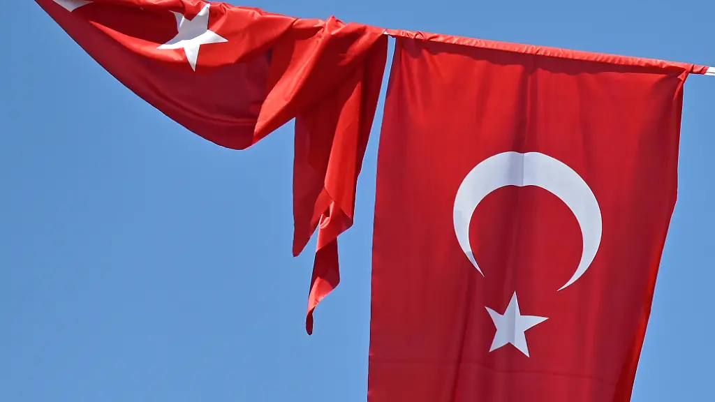 ARCHIV-26-04-2026-Tuerkei-Istanbul-Eine-tuerkische-Flagge-weht-vor-blauem-Himmel-im-Wind-waehrend-eine-zweite-Flagge-aufgewickelt-daneben-haengt
