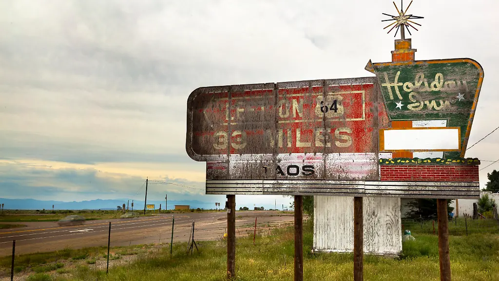 July-14-2915-Monte-Vista-Colorado-USA-284-HWY-South-outside-of-Taos-New-Mexico-Holiday-Inn-sign-A-woman-who-has-lived-in-New-York-since-1924-gets-married-becomes-a-mother-of-3-boys-and-is-an-artist-realizes-in-her-80-s-she-can-no-longer-live-on-her-own-Suzanne-Krieger-is-now-about-to-journey-from-the-east-coast-of-New-York-to-the-American-West-in-Colorado-USA-to-become-a-permanent-resident-at-the-Veterans-Center-at-Homelake-Colorado-Visiting-Mom-is-a-photographic-series-documenting-her-relocation-to-a-new-life-but-also-including-the-underneath-story-about-American-car-travel-since-so-much-of-our-time-was-involved-being-in-a-car-The-vehicle-became-a-player-in-the-story-and-large-part-of-the-visual-experience-I-live-in-Manhattan-I-don-t-drive-much-Spending-so-many-hours-in-a-car-I-started-to-see-the-car-door-and-car-windows-as-an-entrance-or-framing-for-as-visual-narratives-In-the-USA-so-many-people-drive-and-cars-become-an-extension-of-us-I-was-fascinated-by-the-compositions-seen-through-the-car-windows-The-great-American-myth-of-being-on-the-road-was-a-part-of-the-process-The-sense-of-freedom-the-mobility-the-open-spaces