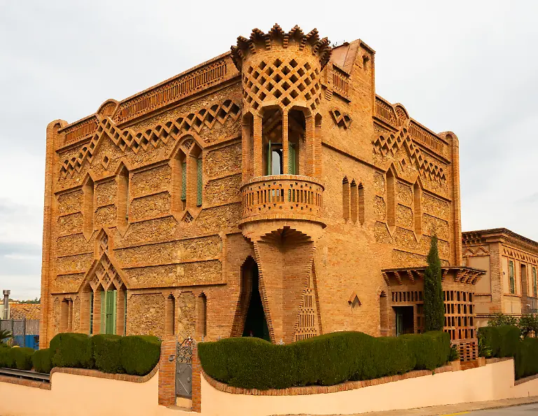 Historical-house-of-factory-manager-of-red-brick-with-corner-in-shape-of-medieval-turret-in-Colonia-Guell-Catalonia-Spain-xkwx-colonia-guell-catalan-spain-european-palace-estate-residence-manor-house-home-manager-director-factory-outdoor-building-construction-architectural-modernist-gaudi-Rubio-bellver-design-ornamented-asymmetrical-facade-medieval-turret-decor-walls-carvings-artworks-creativity-historical-cultural-public-place-spectacular-touristic-traveling-landmark-heritage-monumental-attractions-sightseeing-destination