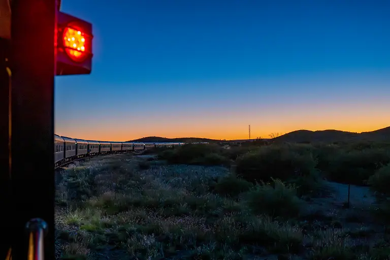 Rotes-Positionslicht-an-Bord-des-luxurioesen-Boutique-Zuges-African-Explorer-von-Rovos-Rail-Lernidee-Erlebnisreisen-in-der-Daemmerung-nahe-Prieska-Nordkap-Suedafrika