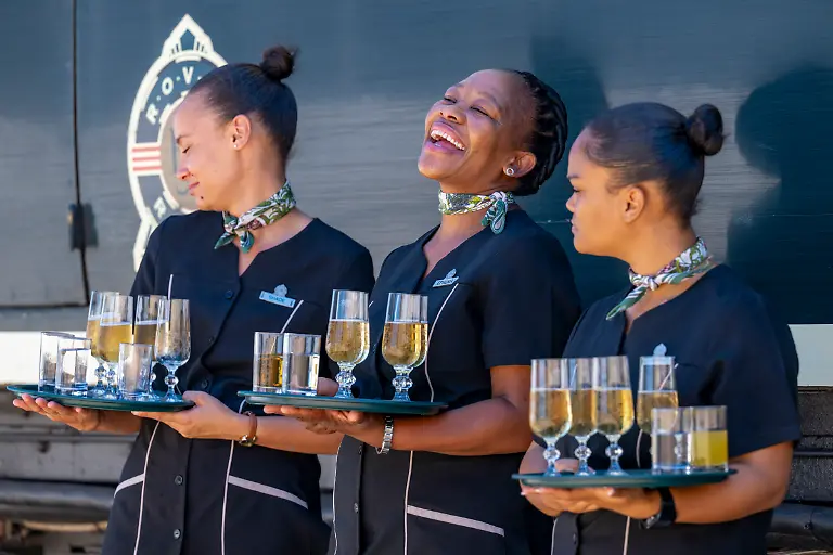 Mitarbeiter-des-Boutique-Luxuszuges-African-Explorer-von-Rovos-Rail-Lernidee-Erlebnisreisen-servieren-Begruessungsgetraenke-fuer-Passagiere-Swakopmund-Erongo-Namibia