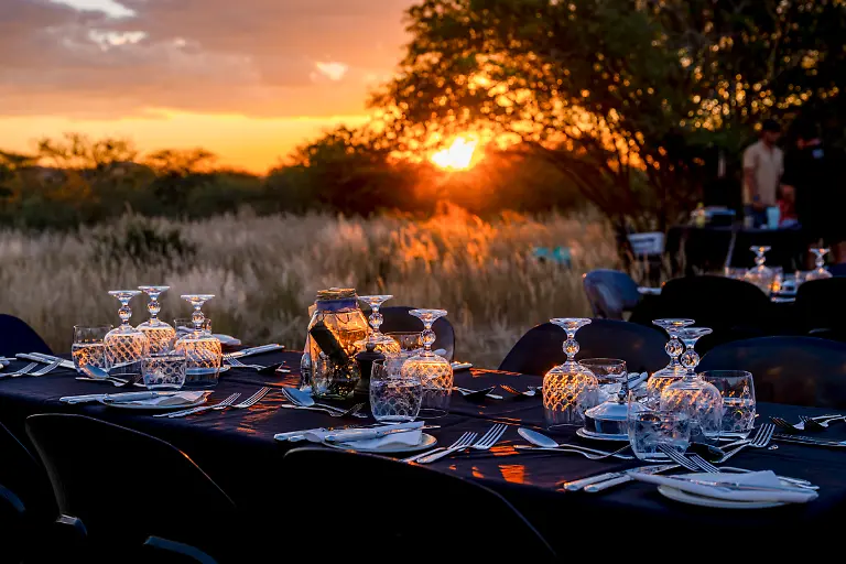 Gedeckter-Tisch-im-Freien-fuer-ein-Braai-Grillabendessen-der-Passagiere-des-luxurioesen-Boutique-Zuges-African-Explorer-von-Rovos-Rail-Lernidee-Erlebnisreisen-bei-Sonnenuntergang-Norman-Erongo-Namibia