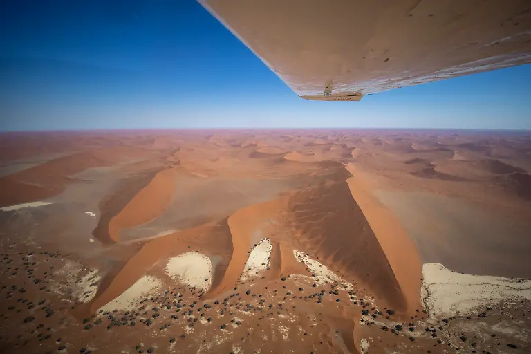 Luftaufnahme-des-Fluegels-einer-Sossusfly-Cessna-210-ueber-riesigen-roten-Sandduenen-in-der-Namib-Wueste-Namib-Naukluft-Nationalpark-Hardap-Namibia
