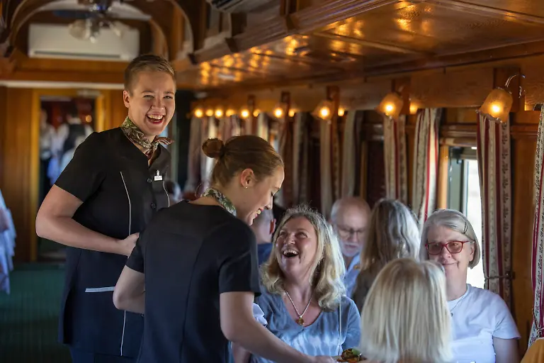 Freundliche-Stewardessen-servieren-das-Mittagessen-in-einem-saeulengeschmueckten-Speisewagen-an-Bord-des-luxurioesen-Boutique-Zuges-African-Explorer-von-Rovos-Rail-Lernidee-Erlebnisreisen-nahe-De-Aar-im-Nordkap-Suedafrika