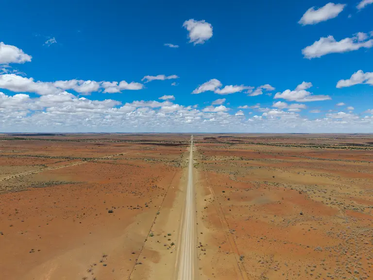 Luftaufnahme-einer-langen-geraden-Schotterstrasse-durch-eine-karge-Landschaft-nahe-Maltahoehe-Hardap-Namibia