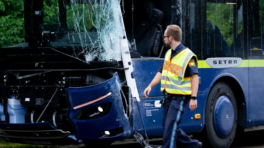 Ein-Linienbus-steht-nach-einem-Zusammenstoss-mit-einem-anderen-Bus-beschaedigt-auf-der-Strasse-Zahlreiche-Grundschueler-sind-in-einem-Reisebus-auf-einer-Strasse-in-Oberbayern-unterwegs-als-es-ploetzlich-zur-Kollision-mit-einem-Linienbus-kommt-Es-soll-mehrere-Verletzte-geben