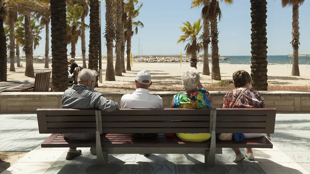 Rueckansicht-von-Touristen-die-sich-auf-einer-Bank-ausruhen-Ausblick-auf-Palmen-und-Strand-Salou-Katalonien-Spanien-Europa-iblpdn03829405