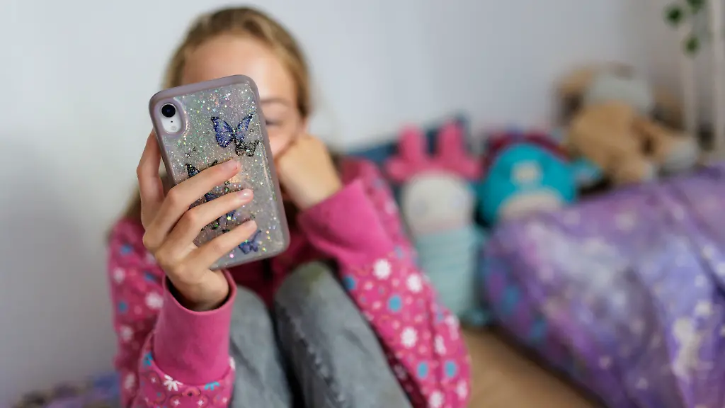 Symbolfoto-zum-Thema-Handynutzung-bei-Kindern-Ein-Maedchen-sitzt-in-ihrem-Bett-und-ist-am-Handy-Berlin-22-07-2025