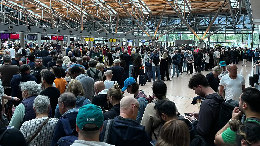 Menschen-stehen-in-einer-Halle-am-Flughafen-in-Hamburg-Wegen-einer-polizeilichen-Lage-am-Hamburger-Flughafen-ist-der-Sicherheitsbereich-des-Airports-geraeumt-worden-Alle-Passagiere-haetten-den-Bereich-hinter-den-Sicherheitskontrollen-verlassen-muessen-sagte-ein-Sprecher-der-Bundespolizei