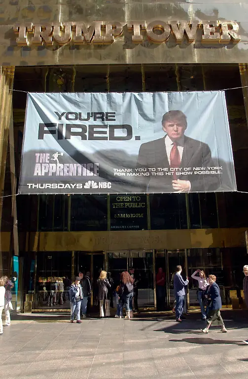 A-sign-with-Donald-Trump-s-image-advertising-the-hit-television-show-The-Apprentice-hangs-from-the-entrance-of-Trump-Tower-on-March-28-2004-President-elect-Donald-Trump-is-expected-to-remain-as-executive-producer-of-The-Apprentice-shown-on-NBC-even-after-he-takes-office-Richard-B