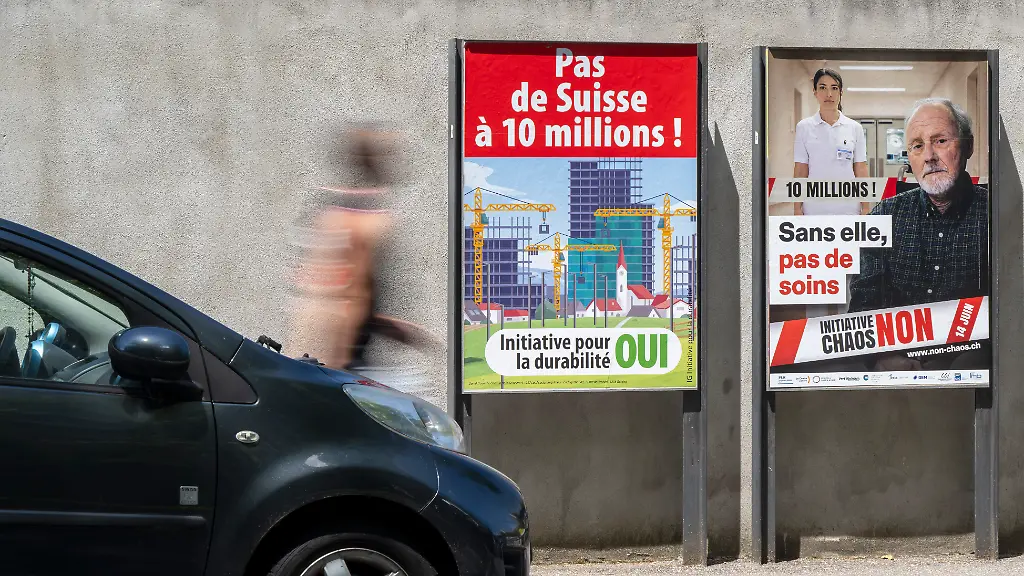Une-personne-passe-devant-les-affiches-des-partis-politiques-et-des-associations-donnant-leurs-mots-d-ordre-pour-les-votations-cantonale-et-federale-du-dimanche-14-juin-ce-dimanche-7-juin-2026-a-Geneve-Les-citoyens-suisses-et-genevois-voteront-sur-plusieurs-objets-federaux-L-initiative-populaire-Pas-de-Suisse-a-10-millions-La-modification-de-la-loi-federale-sur-le-service-civil-Deux-objet-en-votations-cantonale-La-loi-constitutionnelle-modifiant-la-constitution-de-la-Republique-et-canton-de-Geneve-Pour-une-expression-non-ostentatoire-des-conviction-religieuses