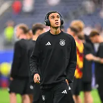 Fussball-Maenner-WM-Deutschland-Curacao-Vorrunde-Gruppe-E-1-Spieltag-Houston-Stadion-Jamal-Musiala-Deutschland-geht-vor-dem-Spiel-mit-Kopfhoerern-ueber-den-Platz-ACHTUNG-Gemaess-den-Auflagen-der-FIFA-duerfen-die-Bilder-ausschliesslich-zur-redaktionellen-Verwendung-genutzt-werden-Eine-kommerzielle-Nutzung-ist-ausgeschlossen-Zudem-duerfen-keine-videoaehnlichen-Sequenzen-erstellt-werden-und-es-duerfen-keine-Veraenderungen-weder-im-Vordergrund-noch-im-Hintergrund-am-Bild-vorgenommen-werden