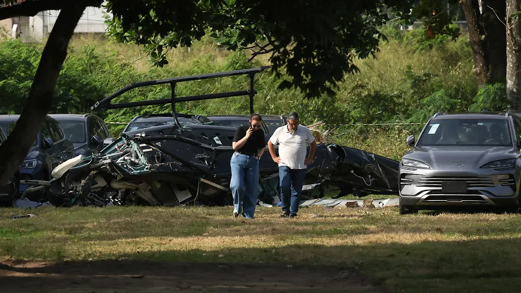 People-walk-near-parts-of-a-helicopter-lying-on-the-ground-following-a-deadly-collision-between-two-helicopters-in-Rio-de-Janeiro-Brazil-June-14-2026