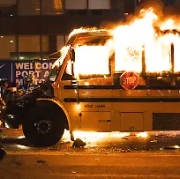 June-14-2026-New-York-New-York-USA-A-man-with-a-white-shirt-on-jumps-in-the-air-with-his-hand-raised-as-he-runs-past-a-yellow-school-bus-that-was-lit-ablaze-during-the-celebration-of-the-New-York-Knicks-winning-the-NBA-Finals