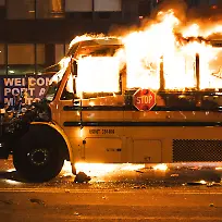 June-14-2026-New-York-New-York-USA-A-man-with-a-white-shirt-on-jumps-in-the-air-with-his-hand-raised-as-he-runs-past-a-yellow-school-bus-that-was-lit-ablaze-during-the-celebration-of-the-New-York-Knicks-winning-the-NBA-Finals