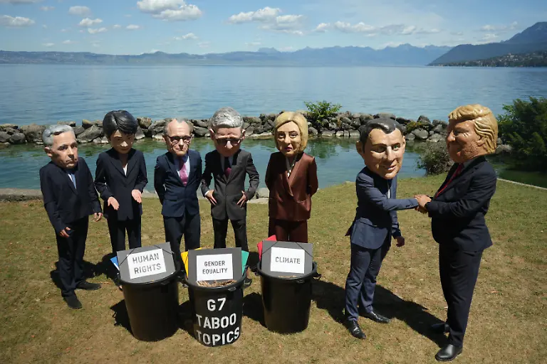 EVIAN-LES-BAINS-FRANCE-JUNE-14-Activists-wearing-oversized-papier-mache-masks-depicting-world-leaders-including-U-S-President-Donald-Trump-and-French-President-Emmanuel-Macron-take-part-in-an-Oxfam-demonstration-ahead-of-the-G7-Summit-in-Evian-les-Bains-France-on-June-14-2026-The-anti-poverty-charity-staged-the-protest-to-call-attention-to-climate-change-and-gender-equality-issues-ahead-of-the-gathering-of-G7-leaders