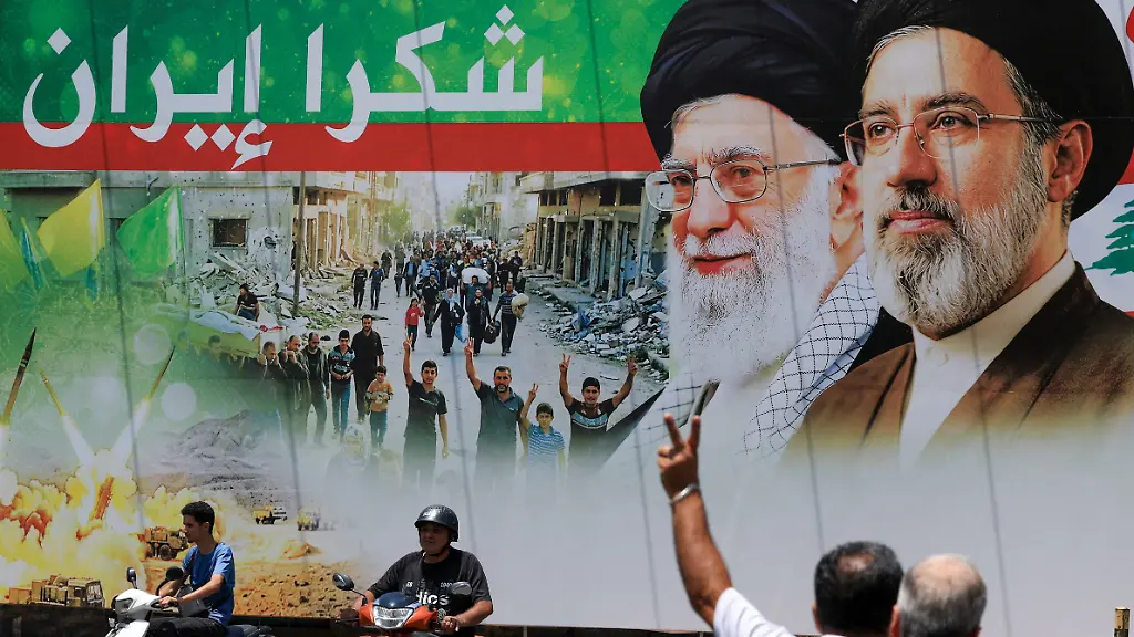 A-man-flashes-a-victory-sign-as-he-rides-a-motorcycle-past-a-banner-that-reads-Thank-you-Iran-following-a-deal-between-the-U-S-and-Iran-in-the-southern-suburbs-of-Beirut-Lebanon-June-15-2026