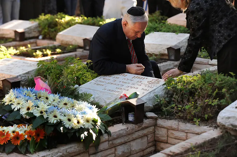 Israel-s-Prime-Minister-Benjamin-Netanyahu-lights-a-candle-by-his-brother-Yonatan-s-grave-during-a-memorial-ceremony-for-him-at-Mount-Herzl-military-cemetery-in-Jerusalem-June-28-2009-Yonatan-Netanyahu-was-killed-while-leading-the-1976-raid-to-rescue-hijacked-Israeli-hostages-from-Entebbe-Uganda