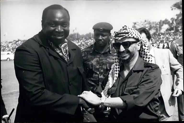 9-September-1975-Arafat-beim-OAU-Gipfel-in-Kampala-Als-Jassir-Arafat-am-Flughafen-Entebbe-ankommt-um-als-Beobachter-am-Gipfeltreffen-der-Staats-und-Regierungschefs-von-OAU-teilzunehmen-wird-er-von-einem-jubelnden-Idi-Amin-begr-t-ausnahmsweise-in-Zivilkleidung
