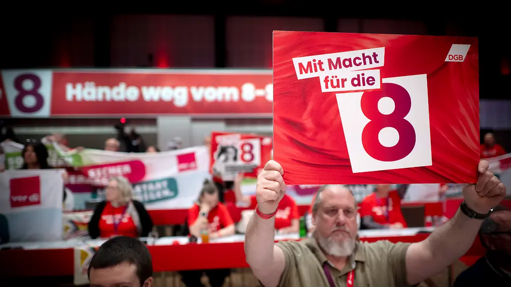 DEU-Deutschland-Germany-Berlin-12-05-2026-Delegierter-mit-Schild-Die-Macht-fuer-die-Acht-8-Haende-Weg-vom-8-Stunden-Tag-als-Protest-waehrend-der-Rede-vom-Bundeskanzler-auf-dem-23-Ordentlichen-Bundeskongress-Deutscher-Gewerkschaftsbund-DGB-unter-dem-Motto-Staerker-mit-uns-in-Berlin-Germany-en-Delegate-with-Sign-Power-to-the-Eight-Hands-Off-the-8-Hour-Day-in-protest-during-the-Federal-Chancellor-s-speech-at-the-23rd-Ordinary-Federal-Congress-of-the-German-Trade-Union-Confederation-DGB-Deutscher-Gewerkschaftsbund-held-under-the-motto-Stronger-with-Us-Staerker-mit-uns-in-Berlin-Germany