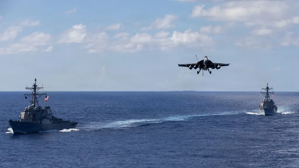 Auf-diesem-von-der-Pressestelle-des-Pentagons-zur-Verfuegung-gestellten-Bild-fahren-die-Lenkwaffenzerstoerer-der-Arleigh-Burke-Klasse-USS-Mahan-l-DDG-72-und-USS-Bainbridge-DDG-96-in-Formation-waehrend-ein-F-A-18-Super-Hornet-des-Carrier-Air-Wing-Eight-zur-Landung-auf-dem-Flugzeugtraeger-USS-Gerald-R-Ford-CVN-78-ansetzt