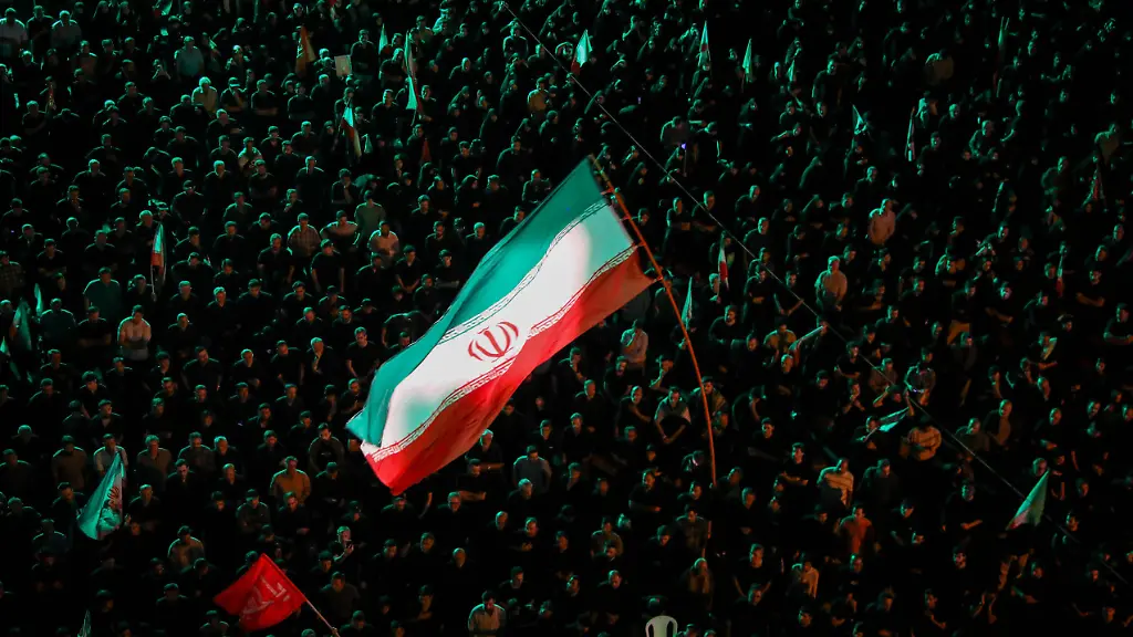 June-17-2026-Tehran-Iran-A-large-Iranian-flag-is-waved-over-a-crowd-of-pro-government-supporters-during-a-state-organized-rally-in-Iran-The-rally-came-as-the-United-States-and-Iran-moved-toward-a-formal-signing-ceremony-expected-on-Friday-June-19-in-Geneva-for-a-memorandum-of-understanding-aimed-at-ending-a-near-four-month-conflict-triggered-by-U-S-Israeli-strikes-on-Iran-Iran-said-on-June-16-that-talks-with-the-United-States-over-its-nuclear-programme-and-sanctions-relief-were-likely-to-begin-later-in-the-week-while-U-S-President-Donald-Trump-said-the-Strait-of-Hormuz-would-Aaoecompletely-openAaA-once-the-two-sides-signed-their-deal