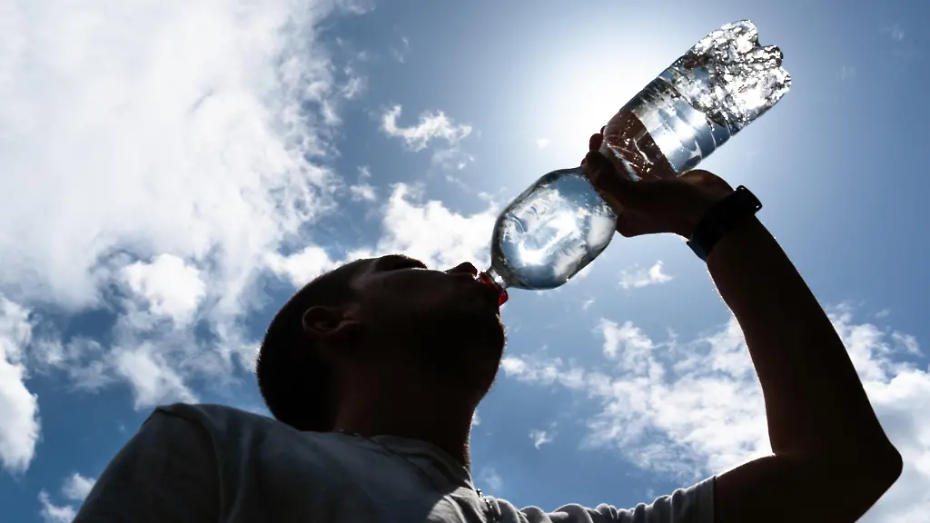 Eine-Person-trinkt-Wasser-unter-direkter-Sonneneinstrahlung-an-einem-heissen-Sommertag
