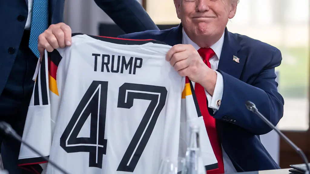 Evian-les-Bains-Frankreich-16-06-2026-Hotel-Royal-G7-Gipfel-US-Praesident-Donald-Trump-haelt-ein-Deutschland-Trikot-hoch-das-er-von-Bundeskanzler-Friedrich-Merz-geschenkt-bekommen-hat-Foto-Michael-Kappeler-Pool-Evian-les-Bains-France-June-16-2026-Hotel-Royal-G7-Summit-U-S
