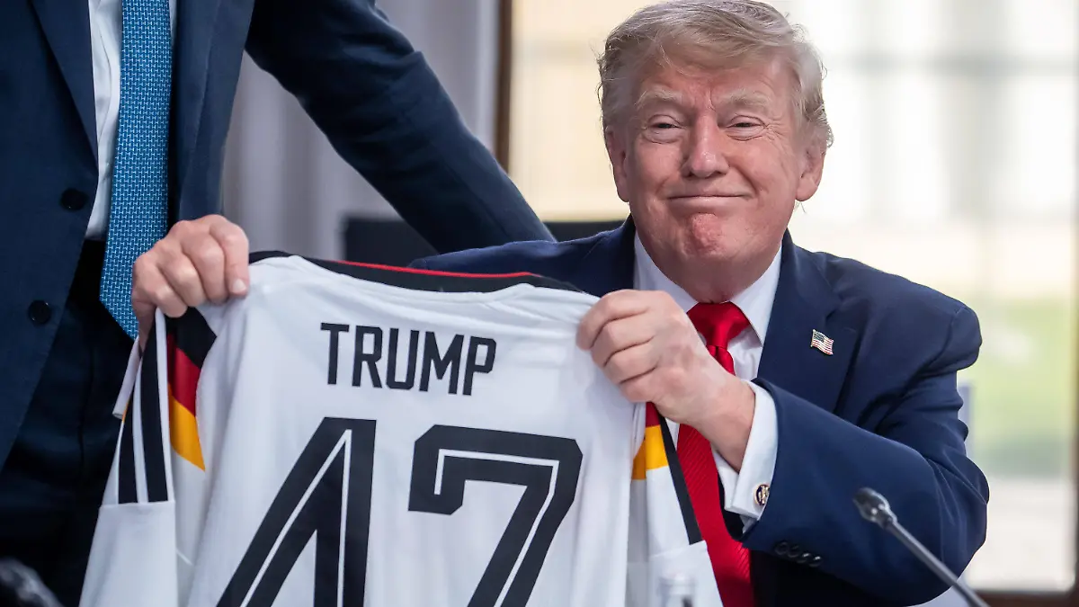 Evian-les-Bains-Frankreich-16-06-2026-Hotel-Royal-G7-Gipfel-US-Praesident-Donald-Trump-haelt-ein-Deutschland-Trikot-hoch-das-er-von-Bundeskanzler-Friedrich-Merz-geschenkt-bekommen-hat-Foto-Michael-Kappeler-Pool-Evian-les-Bains-France-June-16-2026-Hotel-Royal-G7-Summit-U-S