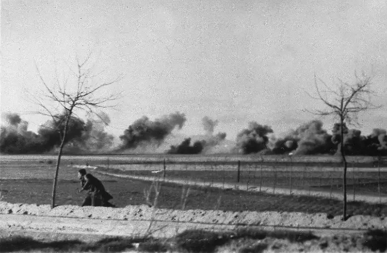 Puffs-of-bomb-smoke-hide-the-mass-disaster-which-has-overtaken-a-small-village-in-the-Guadalajara-as-the-government-presses-its-drive-into-insurgent-held-territory-April-5-1937-during-the-Spain-Civil-War-In-the-foreground-is-an-inhabitant-who-escaped-death