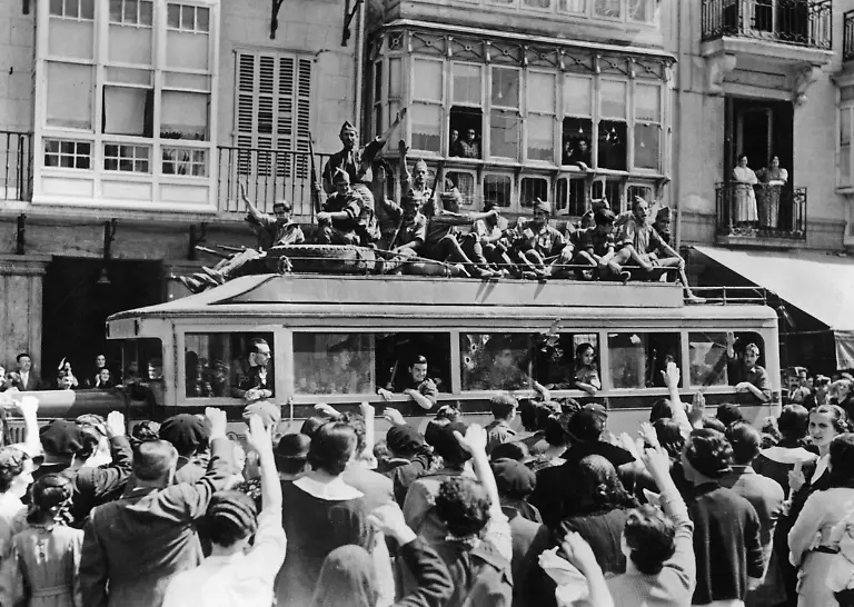 Nationalspanische-Soldaten-unter-Befehl-General-Emilio-Mola-Vidals-1887-bis-1937-werden-im-Spanischen-Buergerkrieg-1936-in-und-auf-einem-Omnibus-zur-Nordfront-bei-Irun-Baskenland-franzoesische-Grenze-gebracht-Die-Menge-jubelt-ihnen-zu-Beide-begruessen-sich-mit-dem-Faschistischen-Gruss-Aufnahmedatum-01-01-1936-31-12