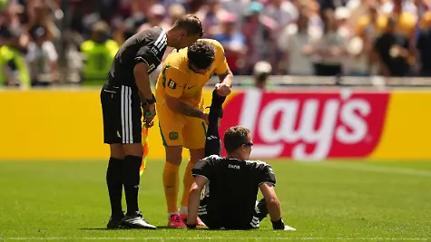 Fussball-Maenner-WM-2026-USA-Australien-Vorrunde-Gruppe-D-Spieltag-2-Seattle-Stadion-Schiedsrichter-Felix-Zwayer-Deutschland-sitzt-auf-dem-Rasen-bekommt-vom-Australier-Aiden-O-Neill-Unterstuetzung
