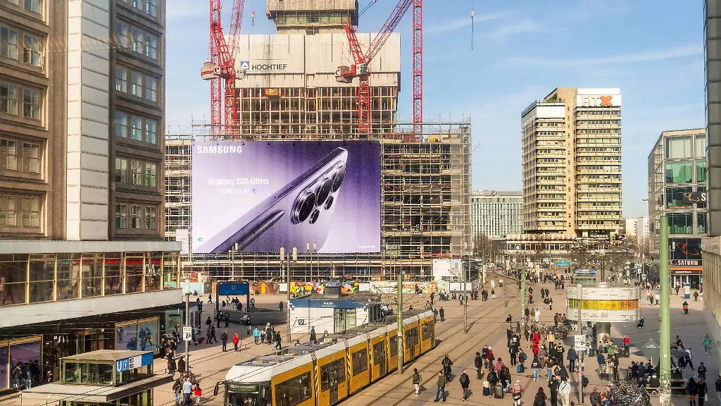 Deutschland-Berlin-Maerz-2026-Alexanderplatz-im-Sonnenschein-Hochhausprojekt-D3-von-Covivio-an-der-Fassade-eine-riesige-Werbeflaeche-von-Samsung-Galaxy-S26-Ultra-Berlin-Mitte-eine-Tram-ueberquert-den-Platz-BVG-Stadt-Immobilien-Baustelle-Verkehr-Wirtschaft-Fruehling
