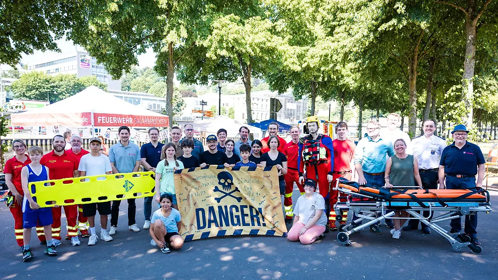 Zum-Abschluss-des-Wasserrettungstags-an-der-Saar-versammeln-sich-Schuelerinnen-und-Schueler-der-Klassenstufen-7-und-9-gemeinsam-mit-Vertretern-von-DLRG-Johannitern-Berufsfeuerwehr-Politik-und-weiteren-Partnern-zum-Gruppenfoto