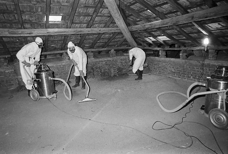 Workers-of-a-cleaning-company-in-protective-gear-and-special-gas-masks-vacuum-the-attic-of-a-residence-with-specifically-designed-vaccum-cleaners-in-Seveso-Italy-on-September-7-2011-On-July-10-1976-a-reactor-explosion-takes-place-at-Icmesa-an-affiliate-of-Givaudan-at-the-periphery-of-the-municipality-of-Meda-near-Milan-in-which-a-cloud-of-dioxin-is-released-The-wind-subsequently-spreads-the-poison-across-a-large-area-and-the-cloud-descends-over-the-neighboring-municipality-of-Seveso