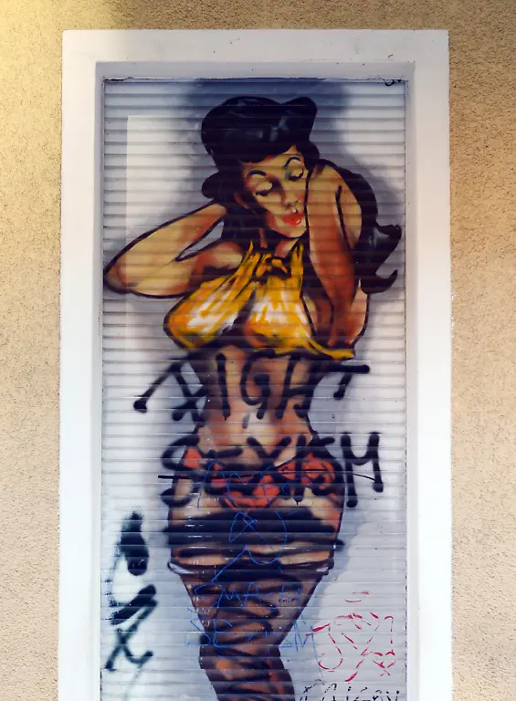 Eine-mit-Graffiti-auf-eine-Jalousie-gespruehte-Frau-die-freizuegig-dargestellt-ist-und-fuer-das-Angebot-eines-Geschaefts-wirbt-ist-am-07-09-2013-in-der-Wuehlischstrasse-in-Berlin-Friedrichshain-mit-dem-Slogan-Fight-Sexism-uebersprueht