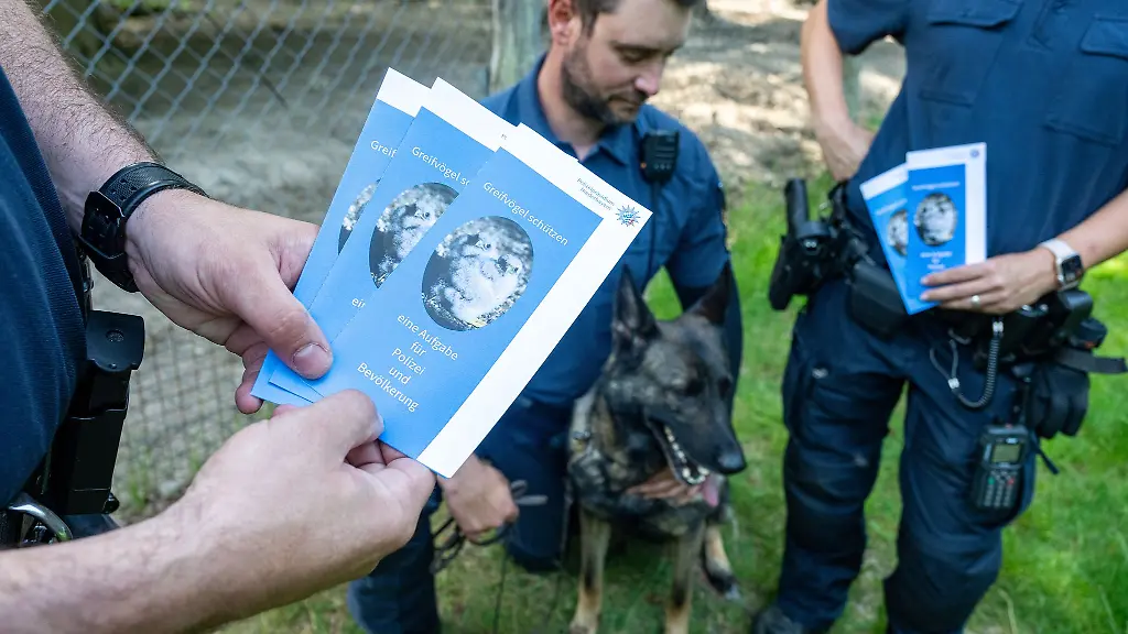 Polizeibeamte-informieren-Spaziergaenger-in-einem-Wald-mit-Infomaterial-ueber-Massnahmen-gegen-Straftaten-an-Wildtieren