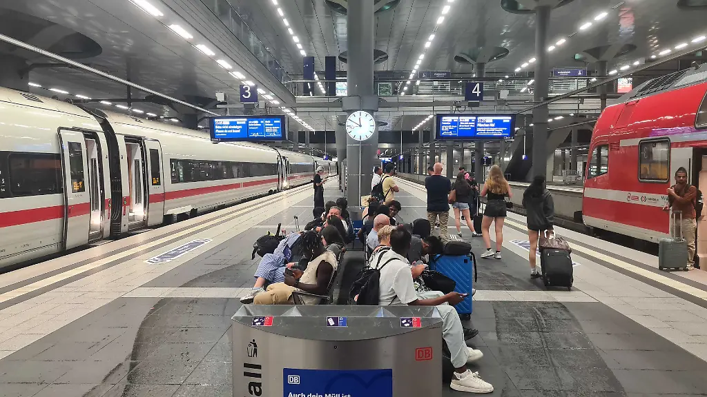 Fahrgaeste-sind-auf-einem-Bahngleis-im-Berliner-Hauptbahnhof-unterwegs-waehrend-Zuege-auf-den-Gleisen-stehen-Der-Verkehr-der-Deutschen-Bahn-ist-wegen-einer-Funkstoerung-bundesweit-eingestellt