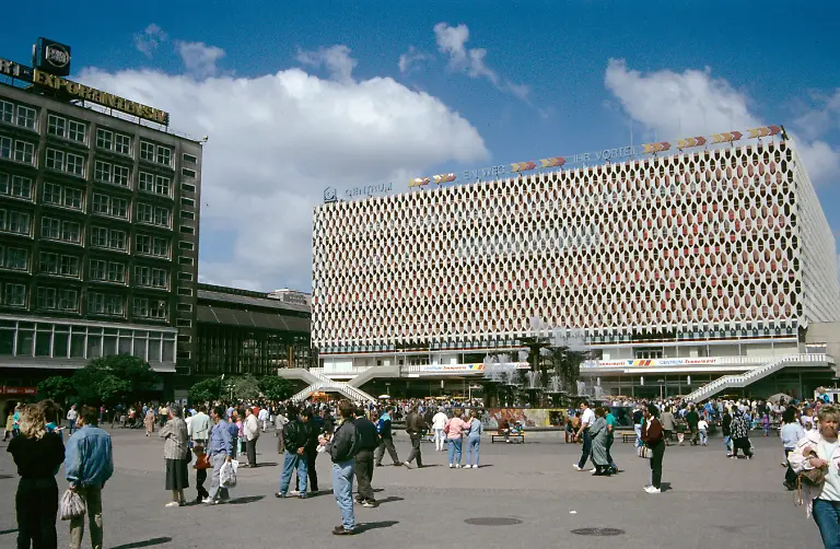 Blick-auf-das-Centrum-Warenhaus-aus-der-DDR-Zeit-am-Alexanderplatz-spaeter-Galeria-Kaufhof-davor-der-Brunnen-der-Voelkerfreundschaft-von-Walter-Womacka-im-Hintergrund-der-S-Bahnhof-Alex-Aufnahme-aus-dem-Mai-1990