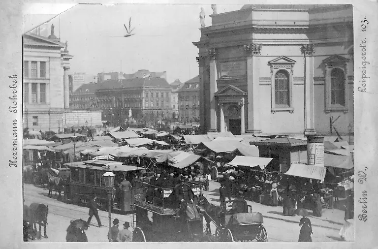 Diese-Fotografie-von-Herrmann-Rohrbek-zeigt-einen-Wochenmarkt-neben-dem-Deutschen-Dom-auf-dem-Gendarmenmarkt-in-Berlin-Mitte-Davor-fahren-von-Pferden-gezogene-Kutschen-und-ein-Tramwagen-Linie-Richtung-Kreuzberg-in-der-Charlottenstrasse-Aufnahme-undatiert-um-1890-entstanden-Aufnahmedatum-01-01-1890-31-12