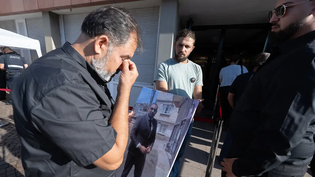 Weinend-wartet-Erdal-Calar-Vater-des-getoeteten-Zugbegleiters-Serkan-Calar-mit-einem-Bild-seines-Sohnes-in-der-Hand-auf-Einlass-in-das-Landgericht