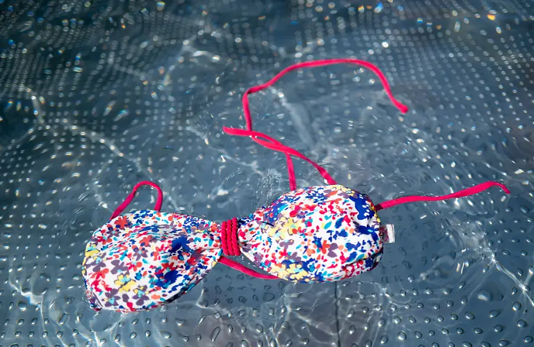 Ein-Bikini-Oberteil-schwimmt-auf-dem-Wasser-in-einem-Freibad-Die-Debatte-ums-Oben-ohne-Baden-fuer-alle-wird-kontrovers-gefuehrt