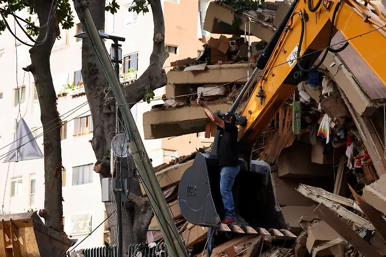 A-man-standing-on-a-digger-s-bucket-cuts-a-wire-near-a-collapsed-building-after-earthquakes-hit-the-country-in-Caracas-Venezuela-June-25-2026