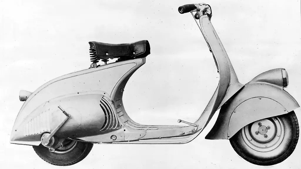 Der-Prototyp-von-1946-hatte-noch-98-ccm-aber-sonst-in-Linienfuehrung-und-Technik-bereits-alle-wesentlichen-Merkmale-der-inzwischen-beruehmt-gewordenen-Vespa-So-die-Anordnung-des-Motors-mit-Direktantrieb-auf-das-Hinterrad-die-selbsttragende-Karosserie-den-feinen-Durchstieg-und-die-einseitig-aufgehaengten-und-untereinander-auswechselbaren-Raeder-Die-Vespa-Nummer-Null-steht-im-Museum-von-Turin
