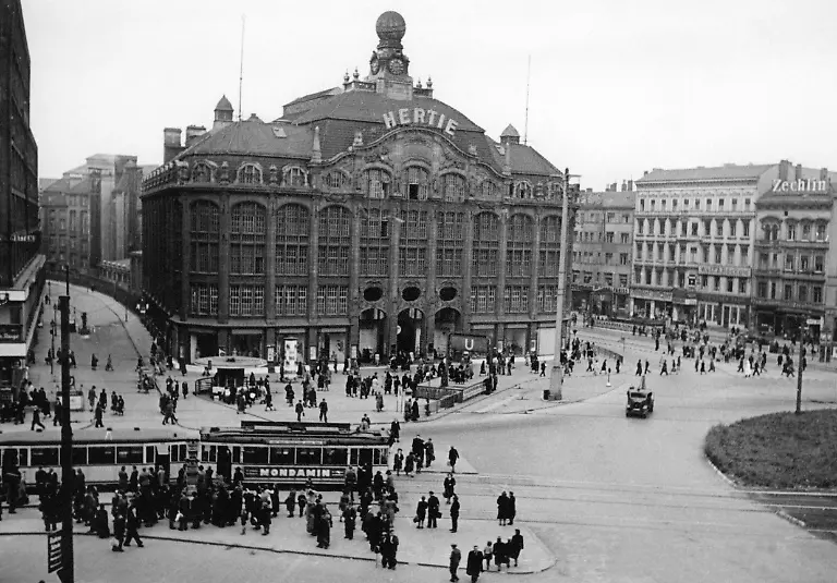 Das-Kaufhaus-Hertie-in-Berlin-Das-Kaufhaus-Tietz-am-Alexanderplatz-in-Berlin-wurde-1904-eroeffent-Fuer-den-Neubau-musste-das-Lessinghaus-weichen-Zur-Zeit-des-Nationalsozialismus-wurde-der-Name-Hertie-aus-den-ersten-Buchstaben-des-Vor-und-Nachnamen-von-Hermann-Tietz-da-der-juedische-Name-nicht-weiter-verwendet-werden-sollte-Zudem-wurde-durch-die-Arisierung-veranlass-dass-Georg-Karg-als-Geschaeftsfuehrer-eingesetzt-wird-der-den-Verkauf-der-Kaufhauskette-abschloss-Hertie-wurde-1994-von-Karstadt-uebernommen-Aufnahmedatum-01-01-1933-31-12