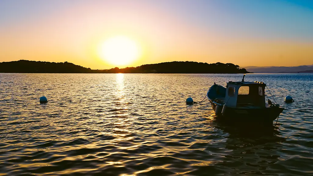 Kleines-Boot-im-Meer-in-der-untergehenden-Sonne